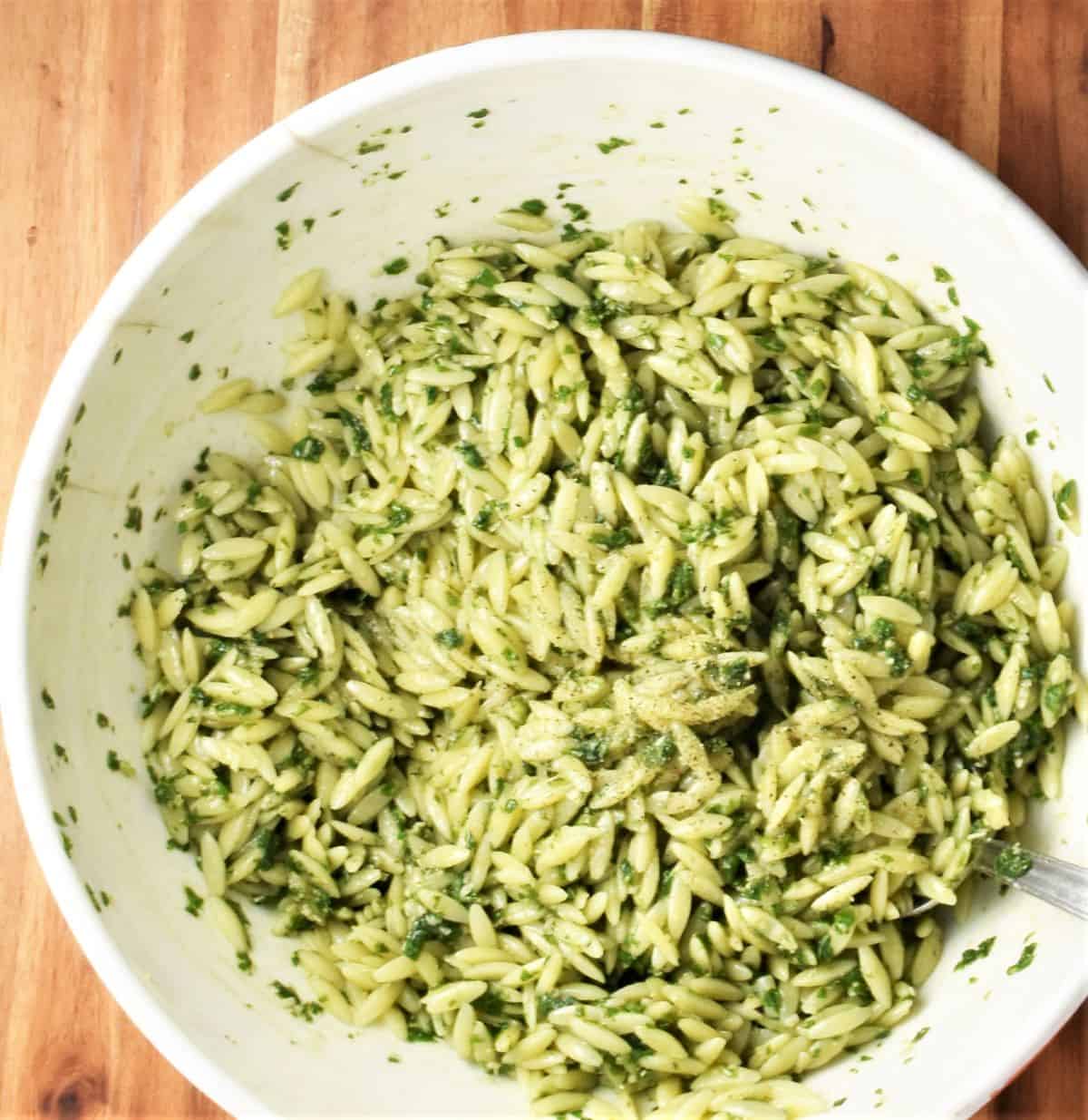 Orzo pasta with pesto sauce in large white bowl.