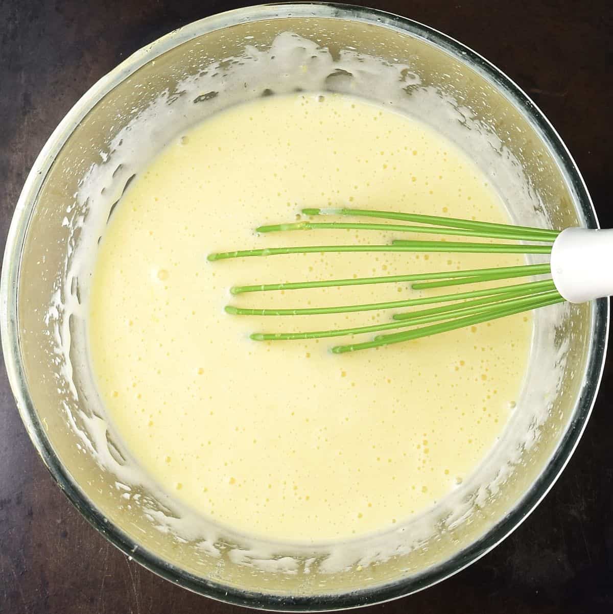 Creamy muffin cake mixture in glass bowl with whisk.