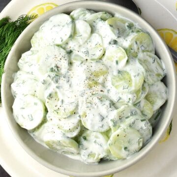 Top down view of Polish cucumber salad with dill and sour cream in grey bowl.