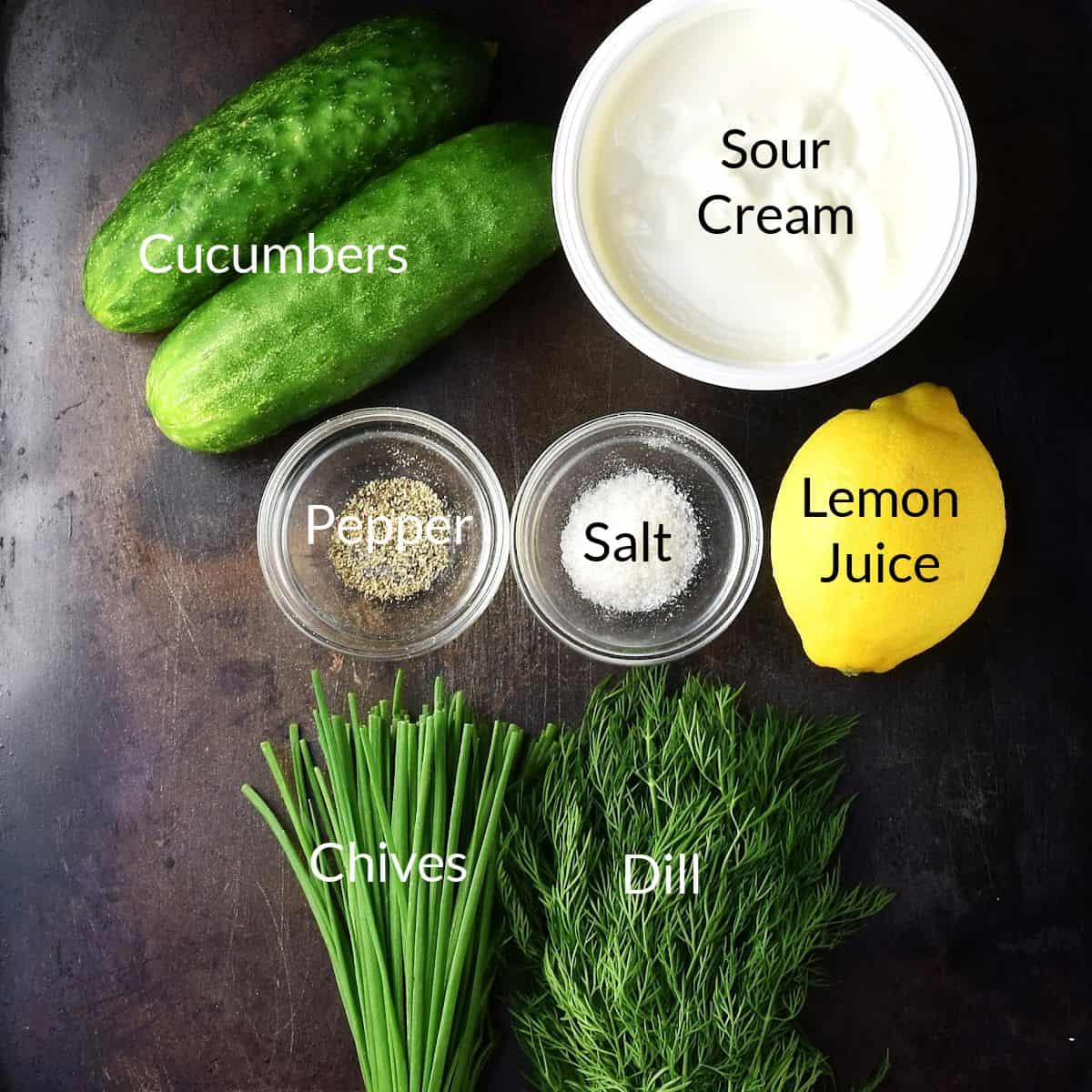 Top down view of Polish cucumber mizeria salad ingredients on top of metal surface.