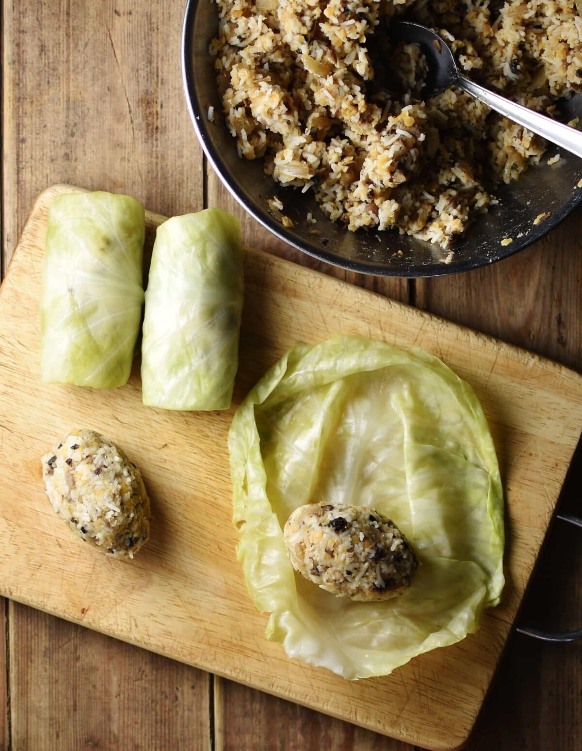Top down view of rolling cabbage leaves with filling in bowl.