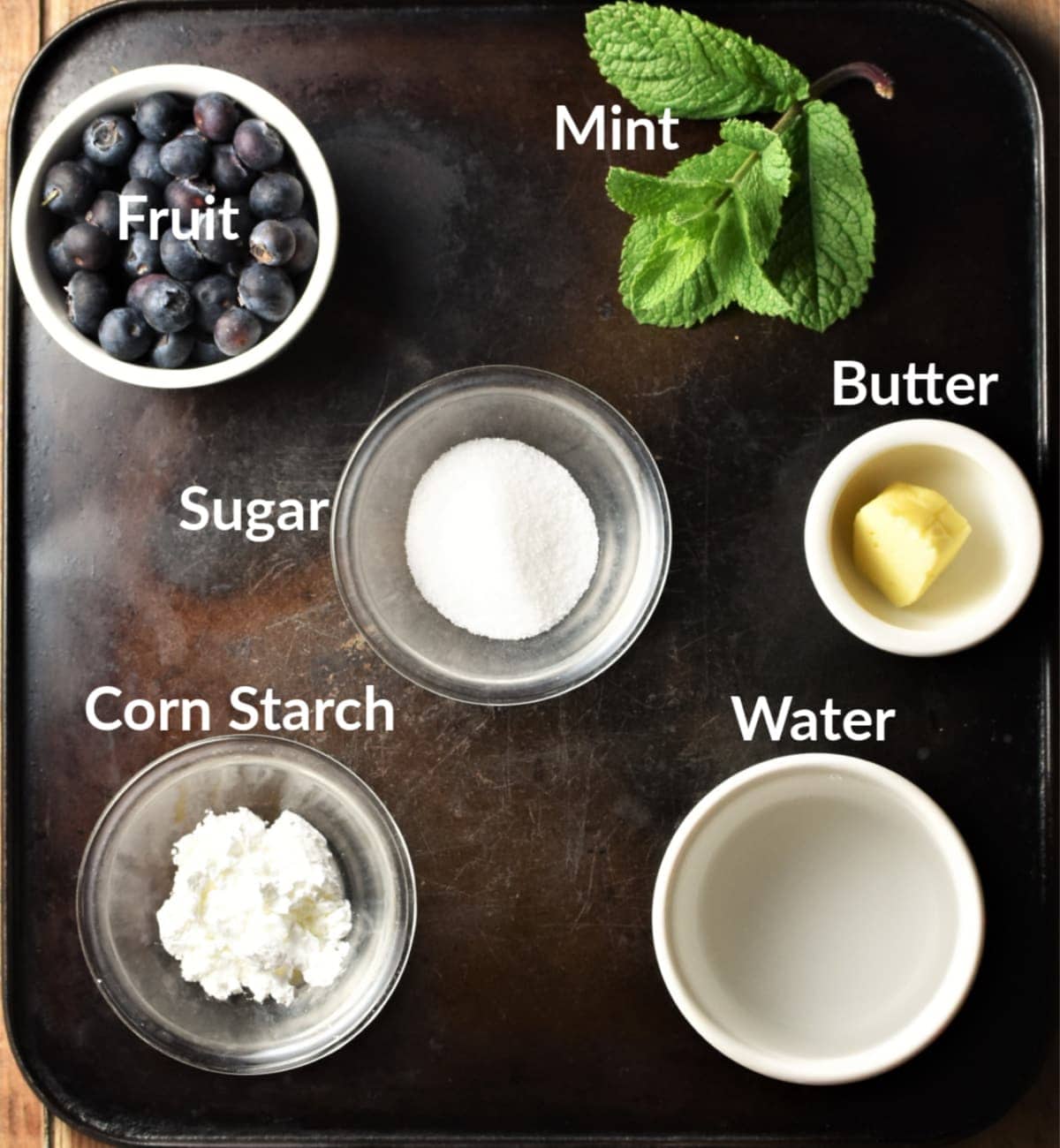 Fruit soup ingredients in individual dishes against black background.