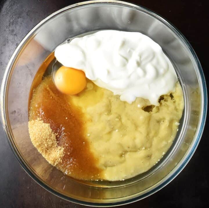 Mashed banana, buttermilk, egg and sugar in glass bowl.