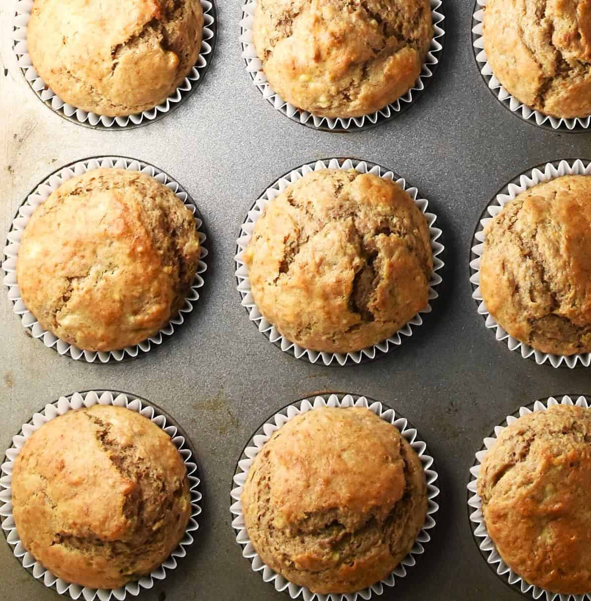 Top down view of baked banana and buttermilk muffins in muffin pan.