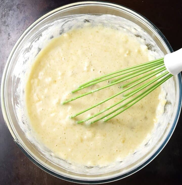Banana and buttermilk muffin wet mixture in glass bowl with whisk.