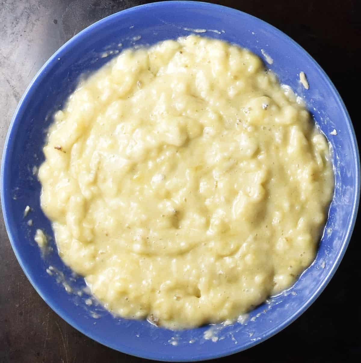 Mashed bananas in shallow blue bowl.