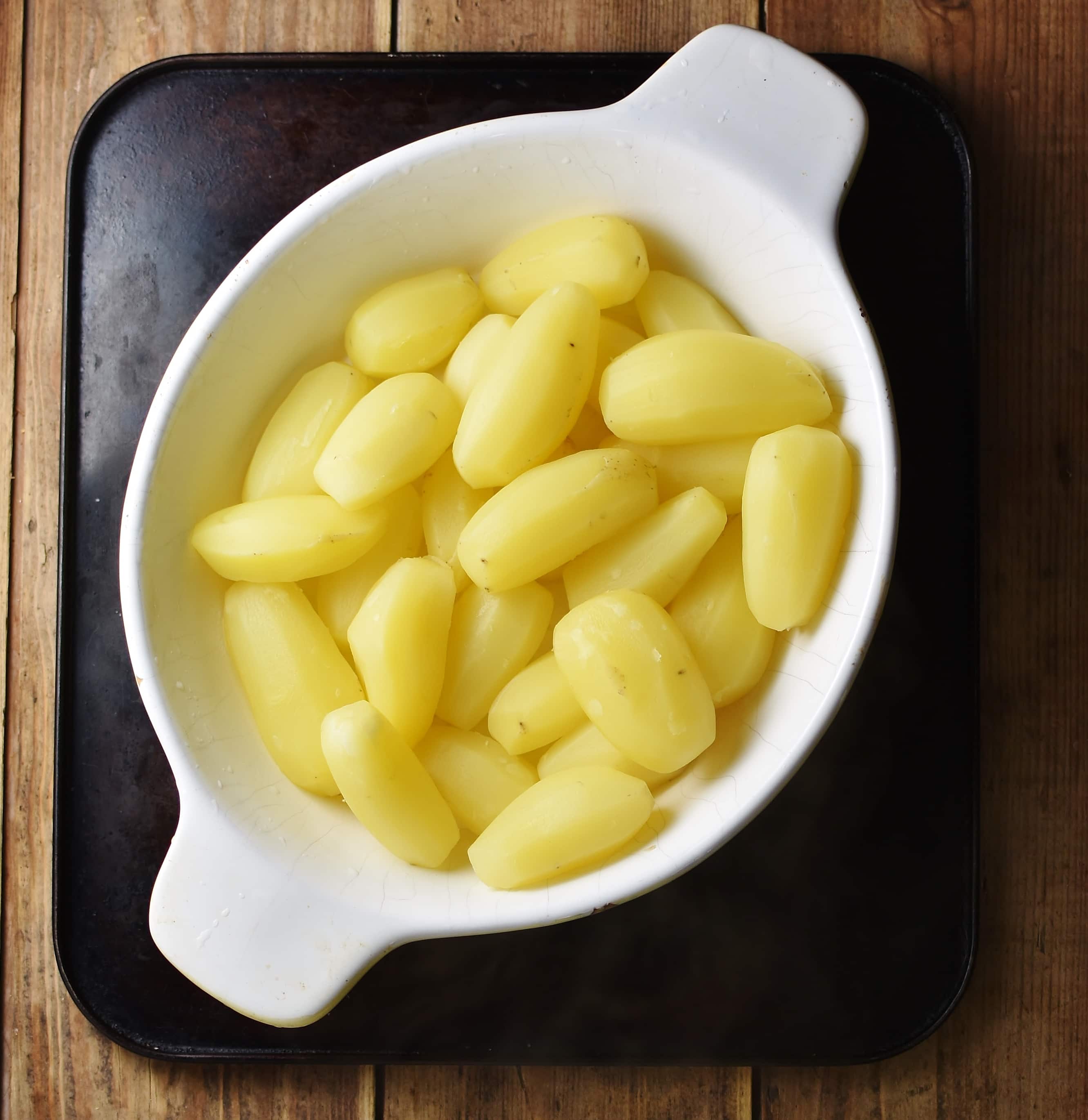Peeled potatoes inside white oval dish.