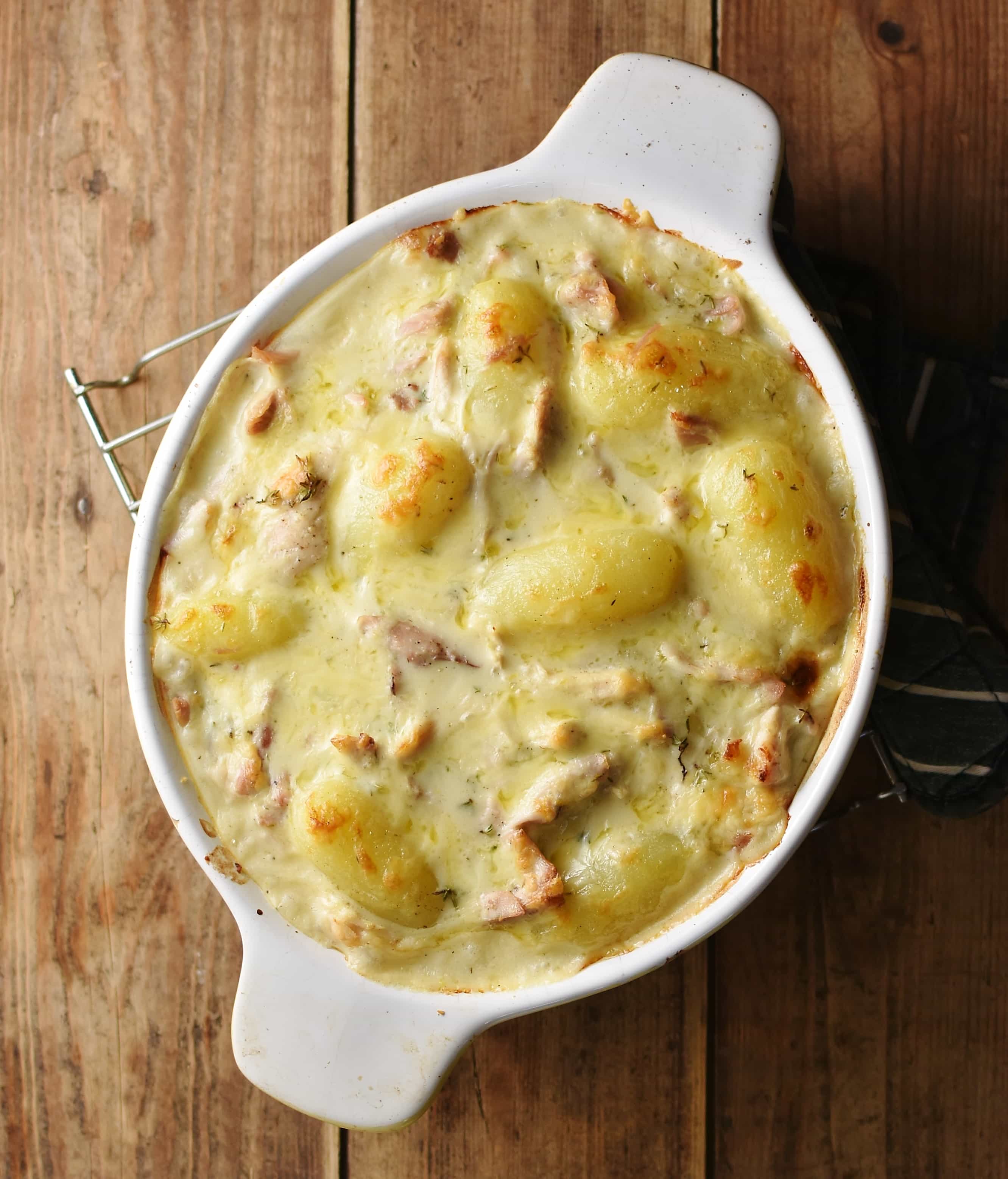 Top down view of creamy chicken and potato casserole in white oval dish.