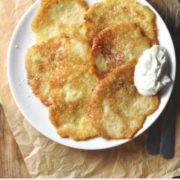 Pancakes with yogurt on top of white plate on sheet of paper.