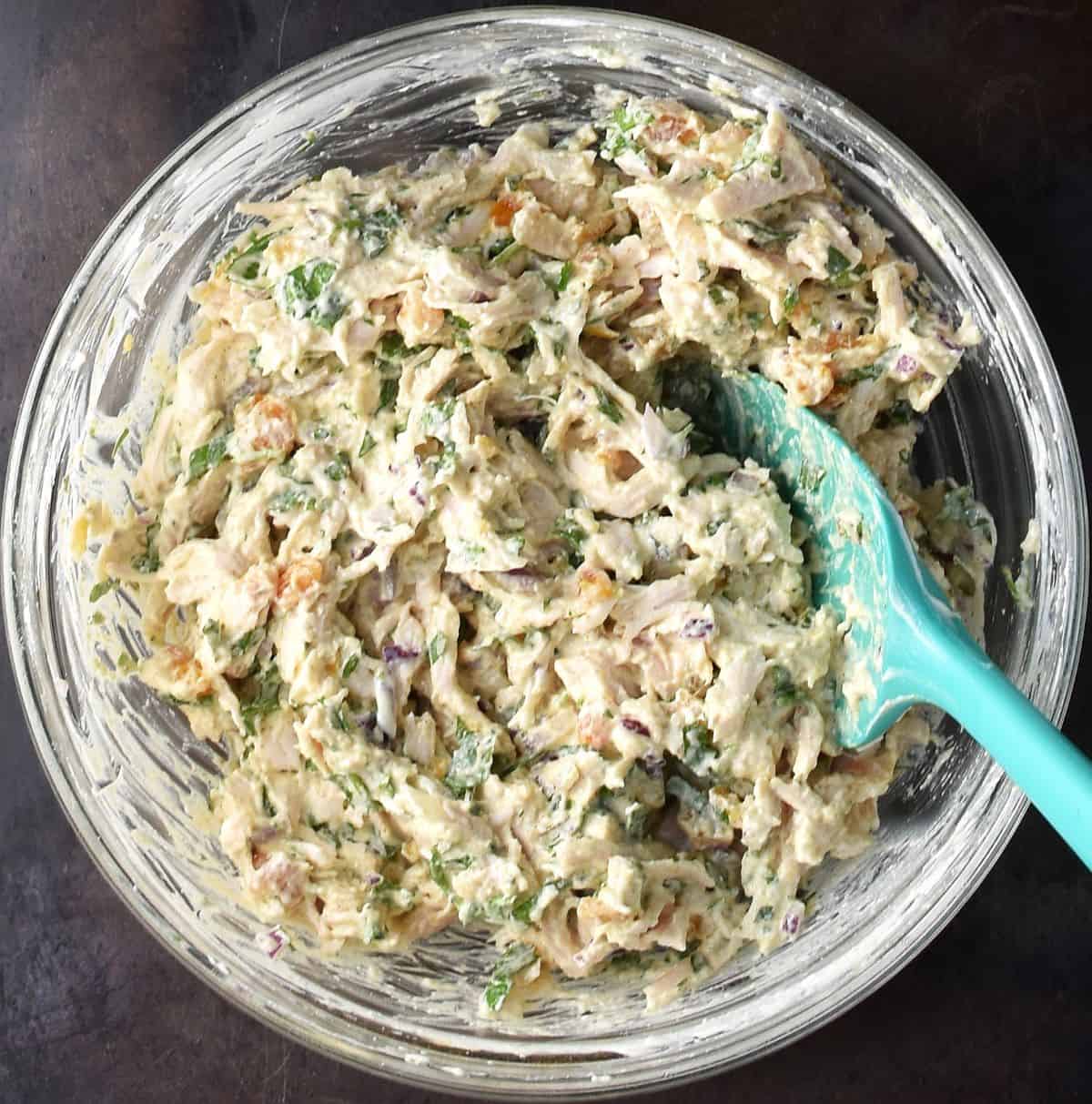 Assembled protein chicken salad in glass bowl with blue spoon.