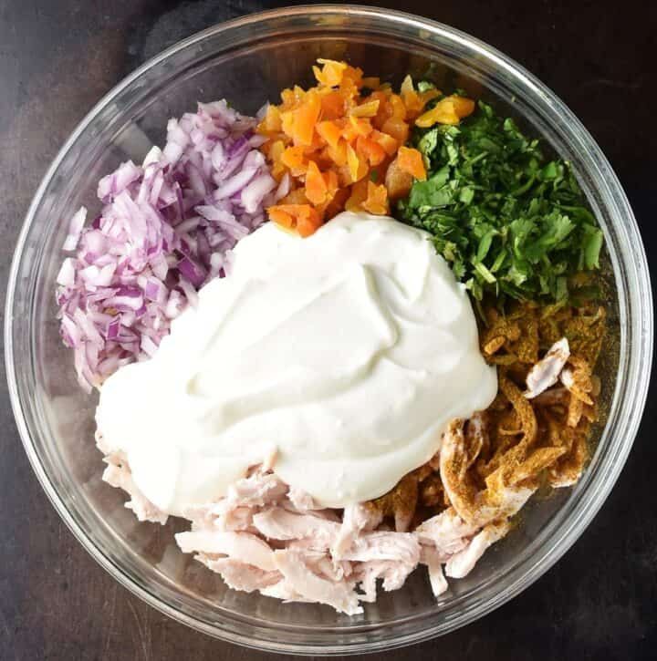 Protein chicken salad ingredients with creamy dressing in glass bowl.
