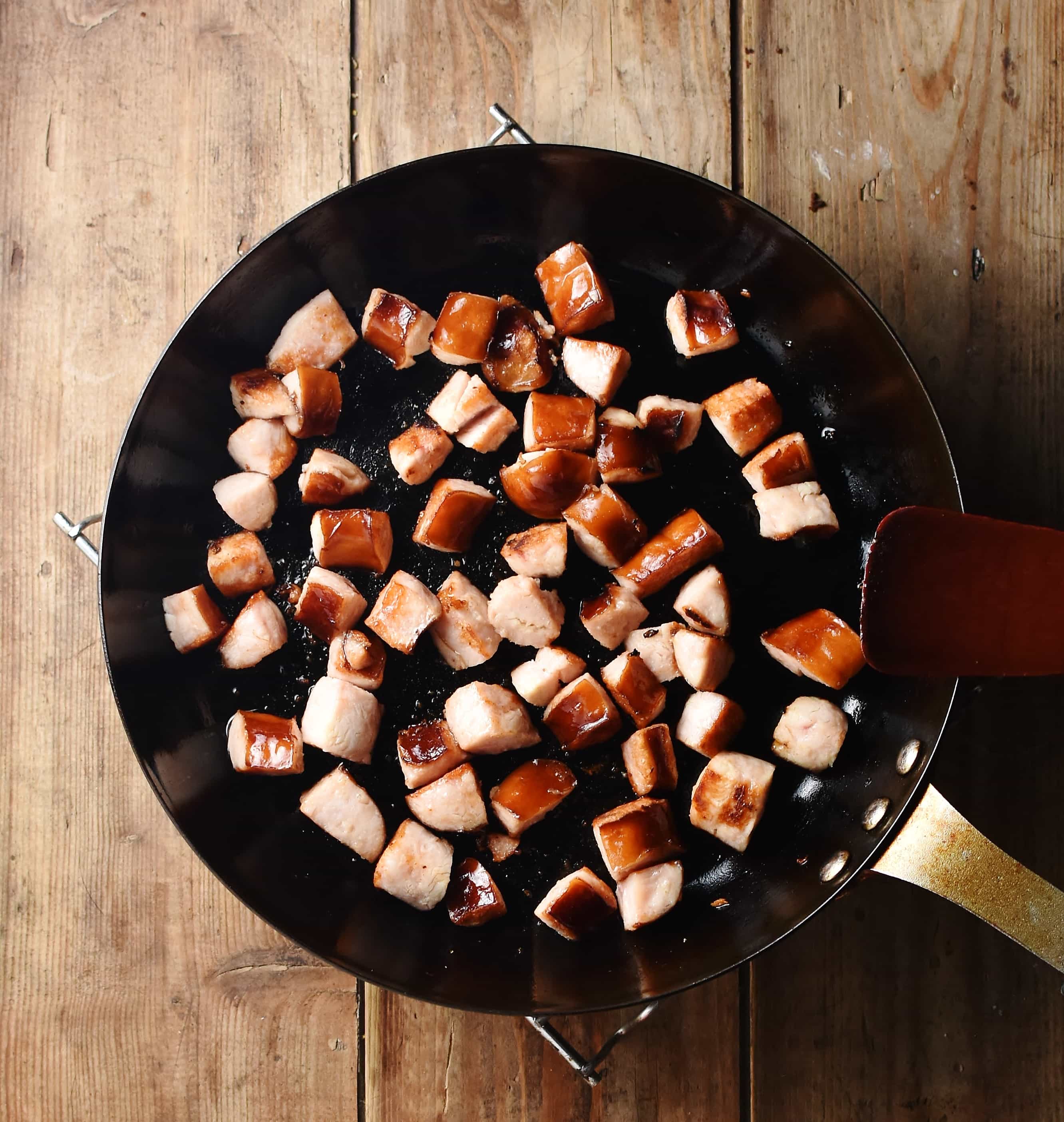 Chopped sausage frying in large pan.