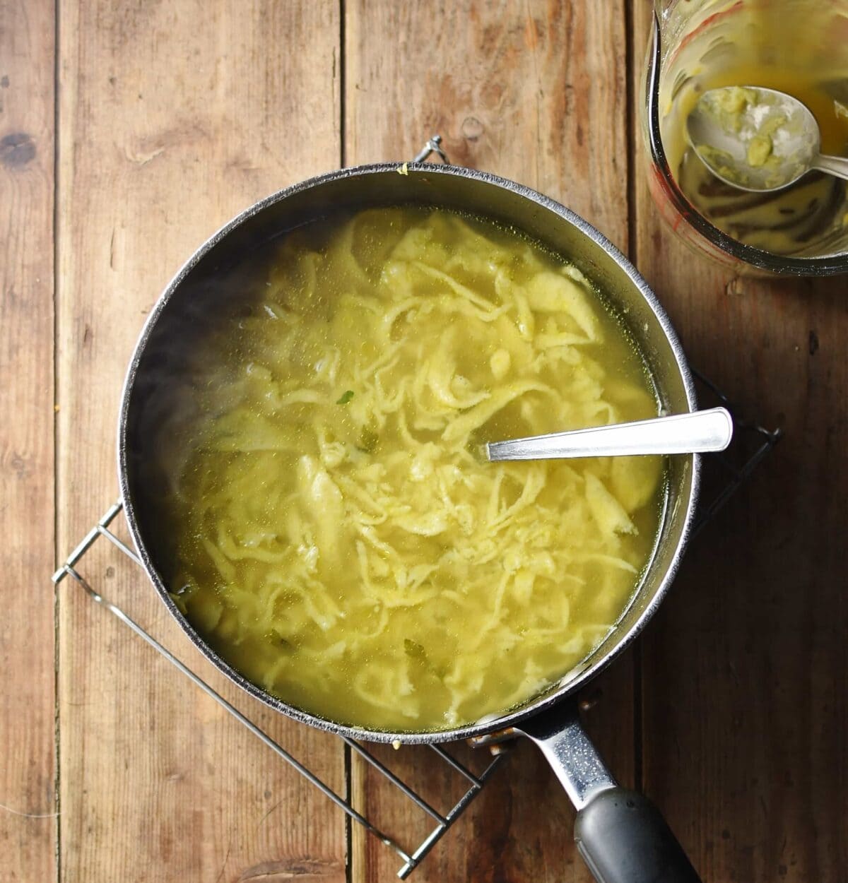 Egg drop soup with spoon in large pot.