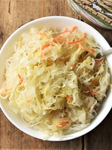 Top down view of sauerkraut in white bowl with spoon.