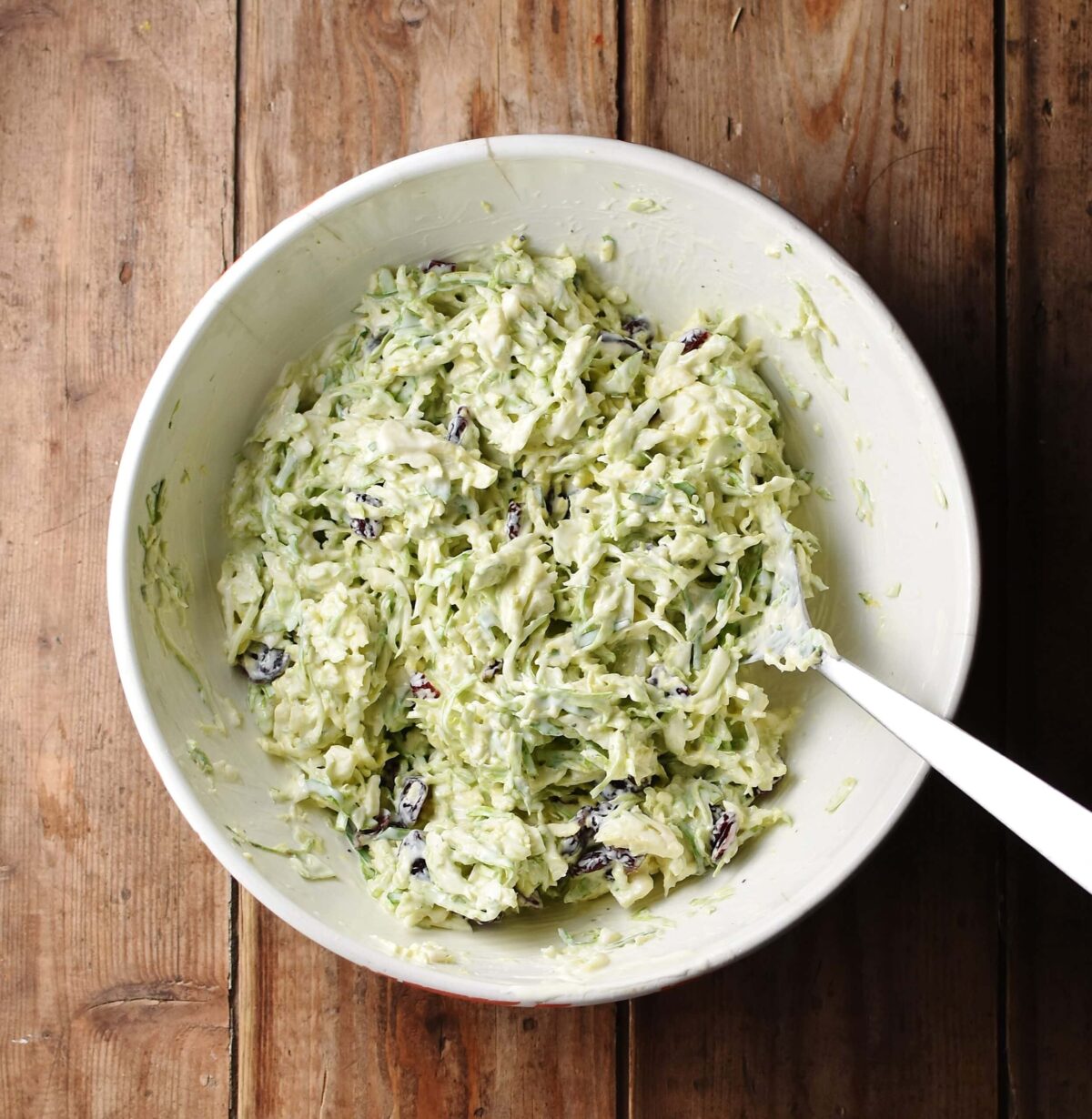 Creamy brussel sprout slaw in large bowl with spoon.