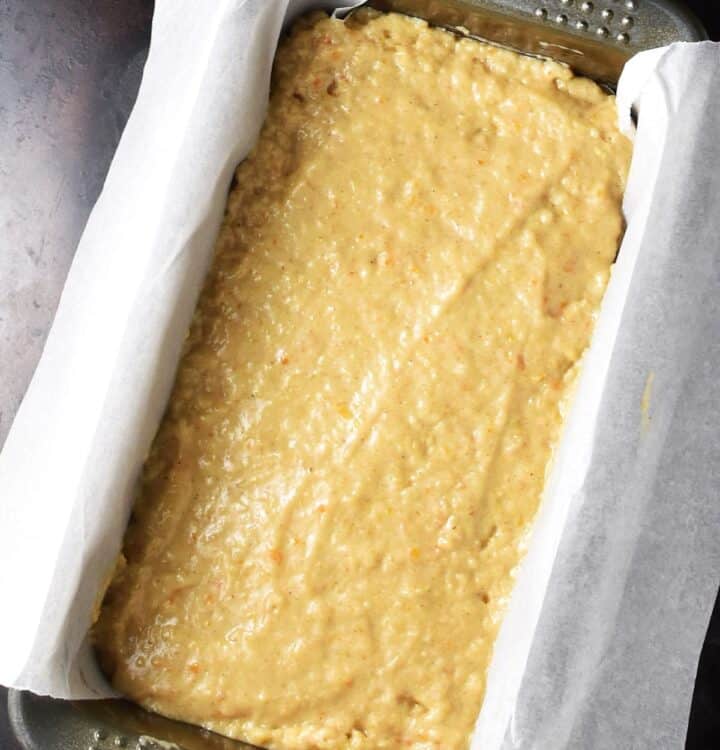 Top down close-up view of persimmon bread batter in loaf pan lined with parchment.
