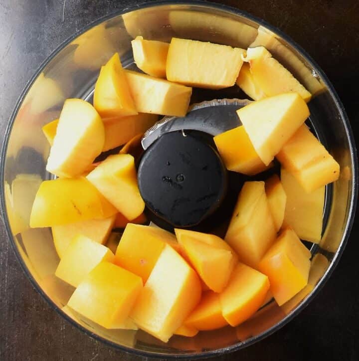 Top down view of cubed persimmon in food processor bowl.
