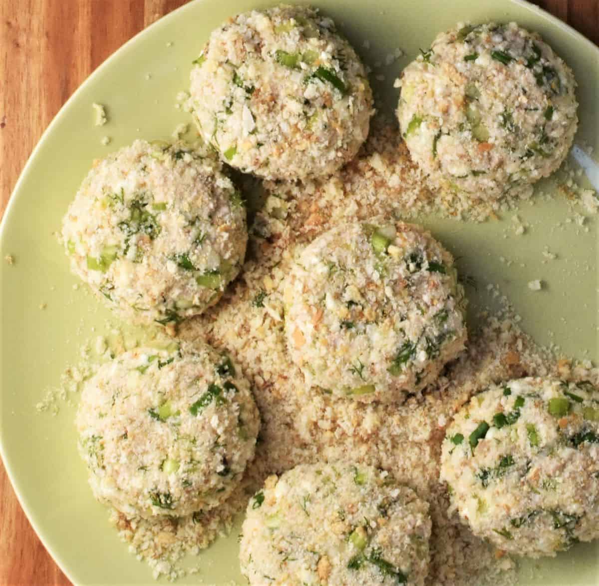 Turkey cakes coated in breadcrumbs on yellow plate.