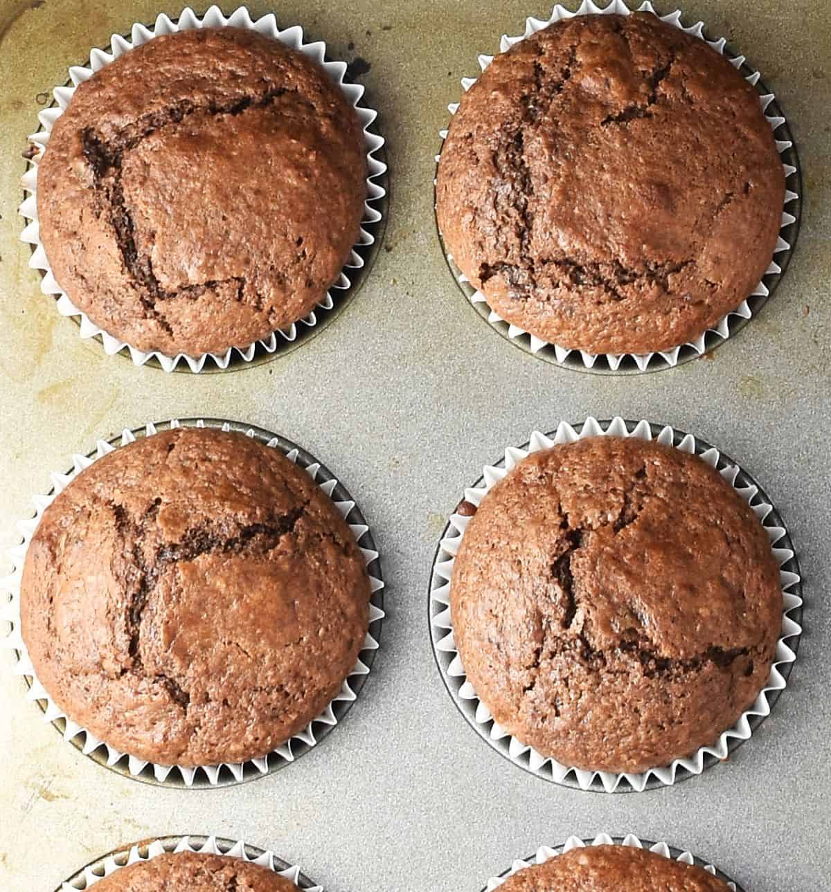 Top down view of 4 baked gingerbread muffins in pan.