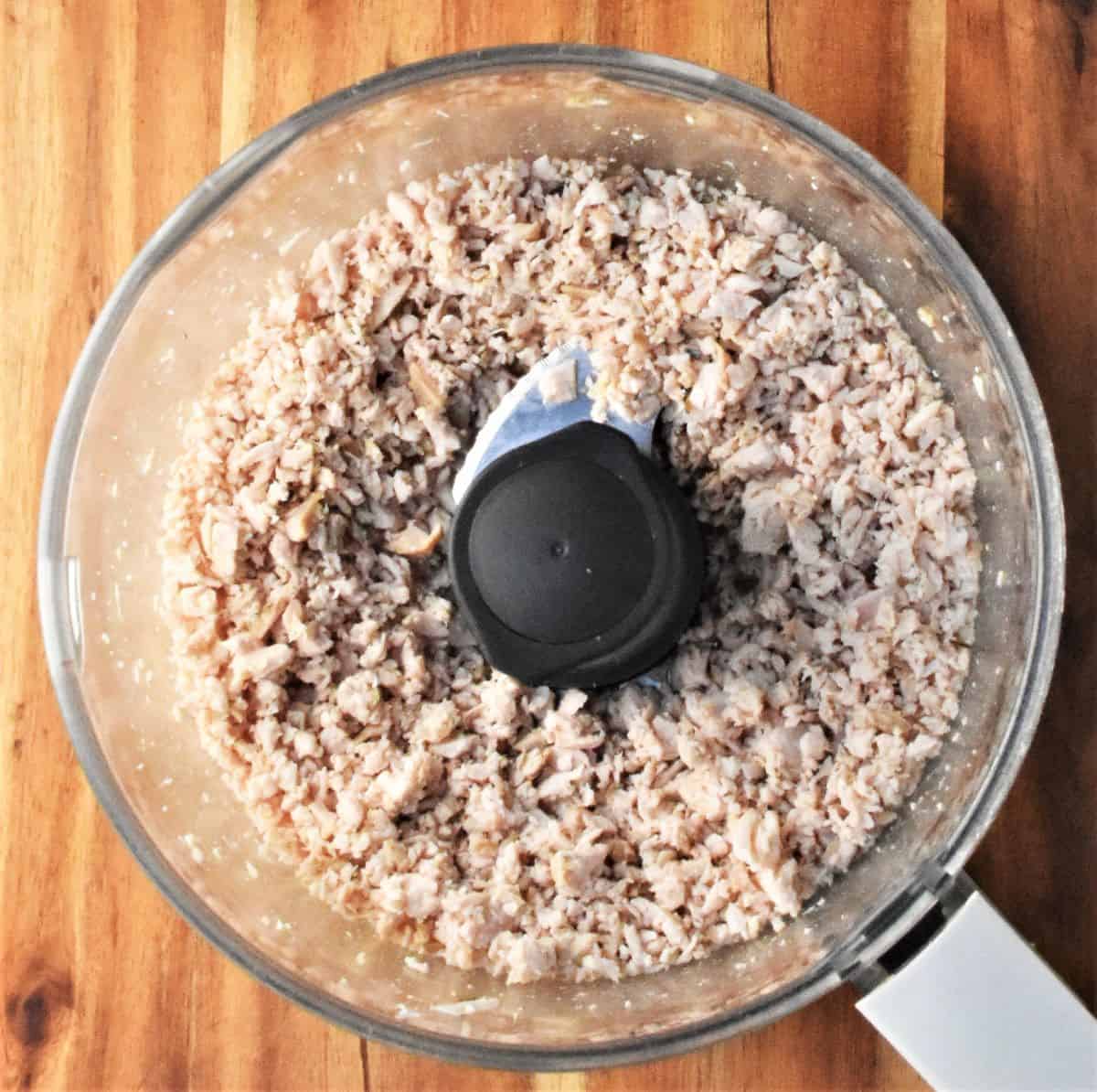Top down view of crumbled turkey meat in food processor.