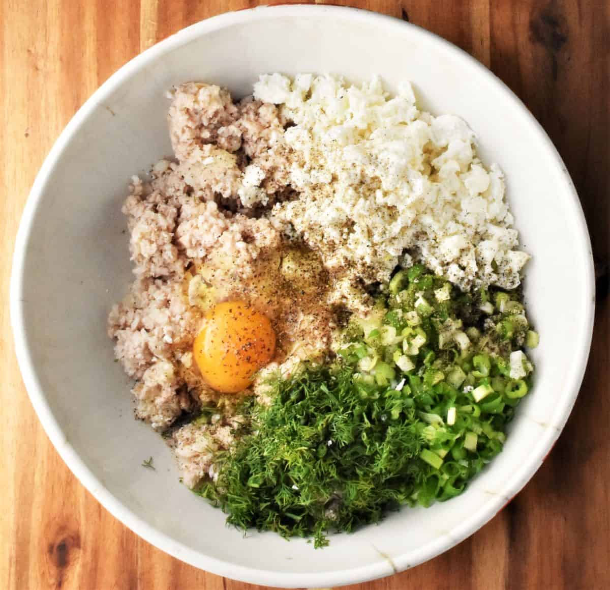 Ingredients for making turkey cakes in large bowl.