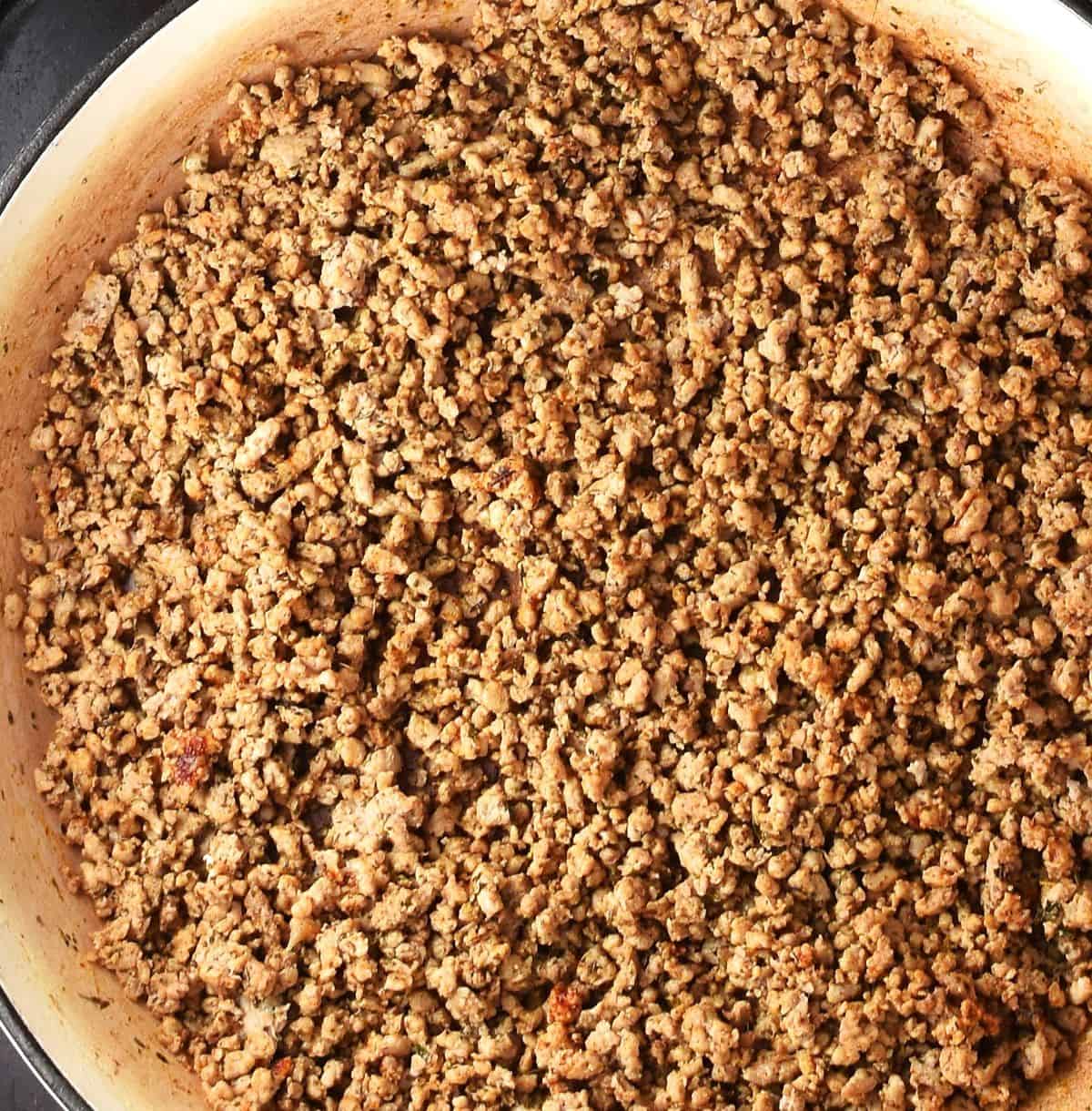 Top down view of browned ground meat in large skillet.
