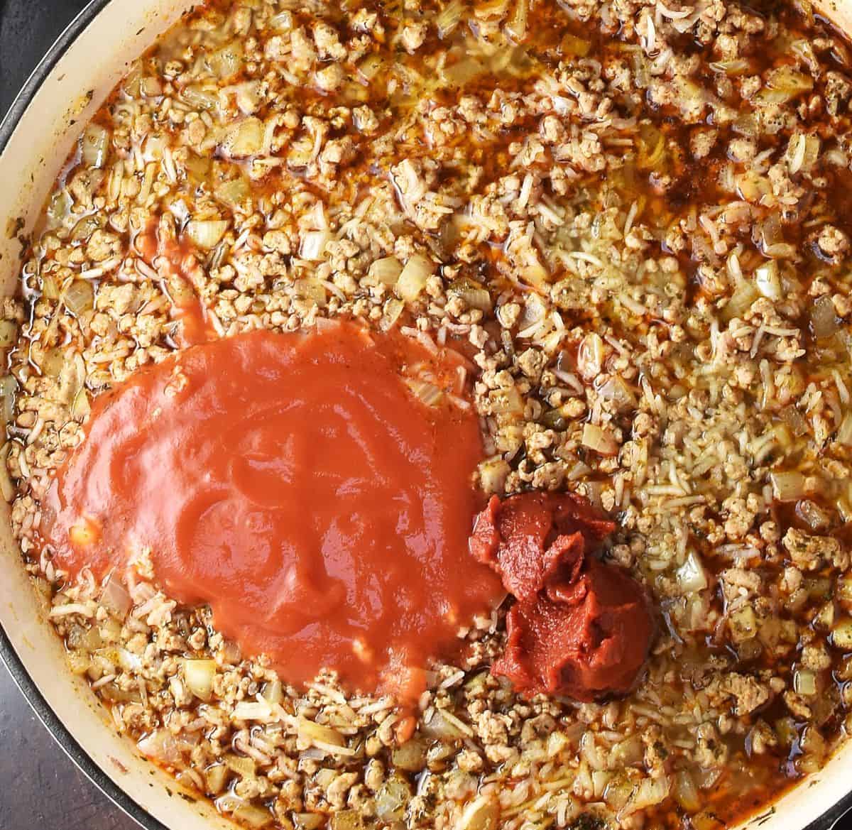 Meat and rice with stock and passata in skillet.