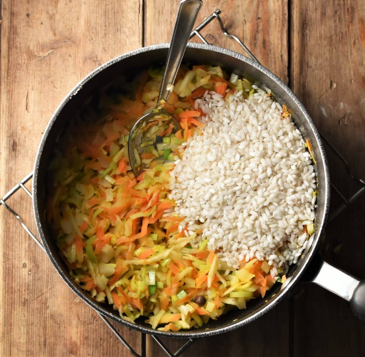 Grated vegetables and rice on large pot with spoon.