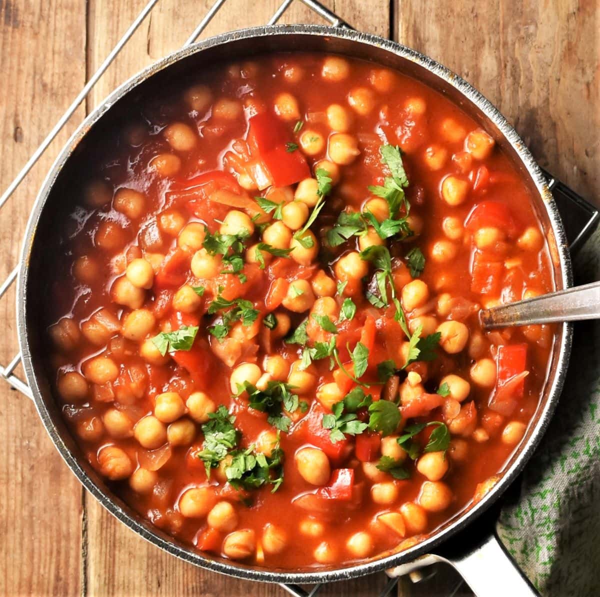 Top down view of chickpea casserole with parsley in pot with spoon.