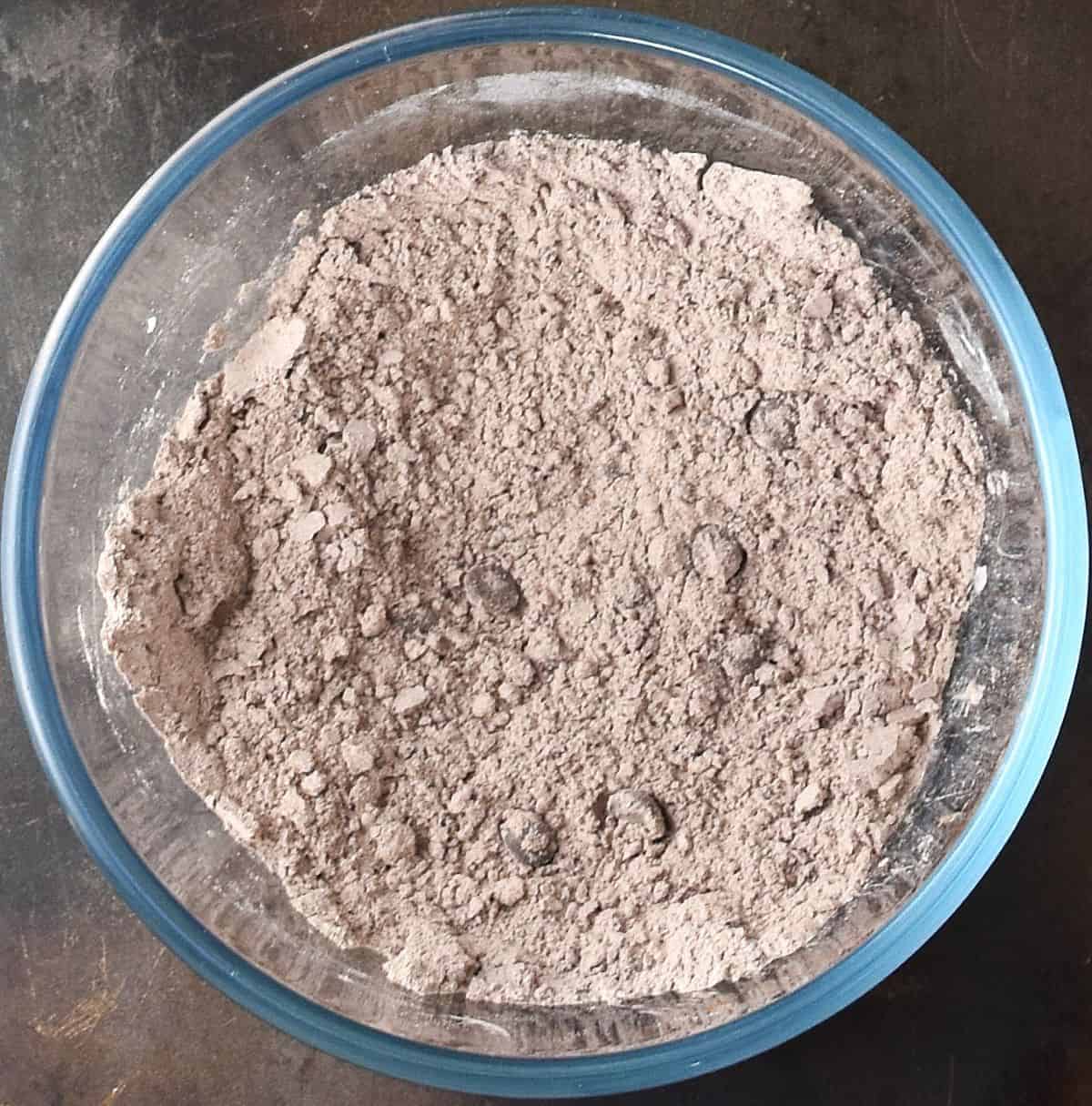 Top down view of dry chocolate coconut muffin mixture in glass bowl.