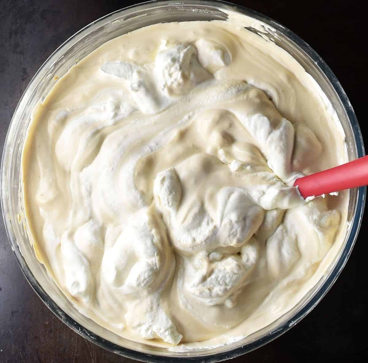 Top down view of coffee cheesecake filling with cream in glass bowl.