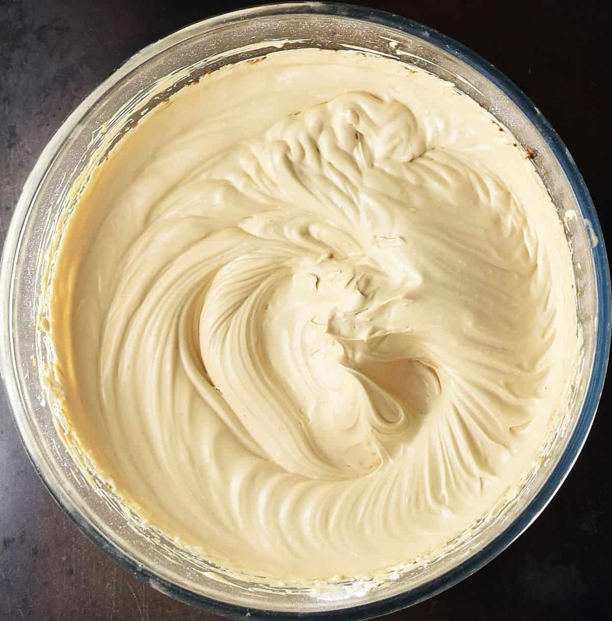 Creamy coffee cheesecake filling mixture in glass bowl.