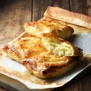 Side view of cheese and onion pasties with cauliflower on top of parchment paper.