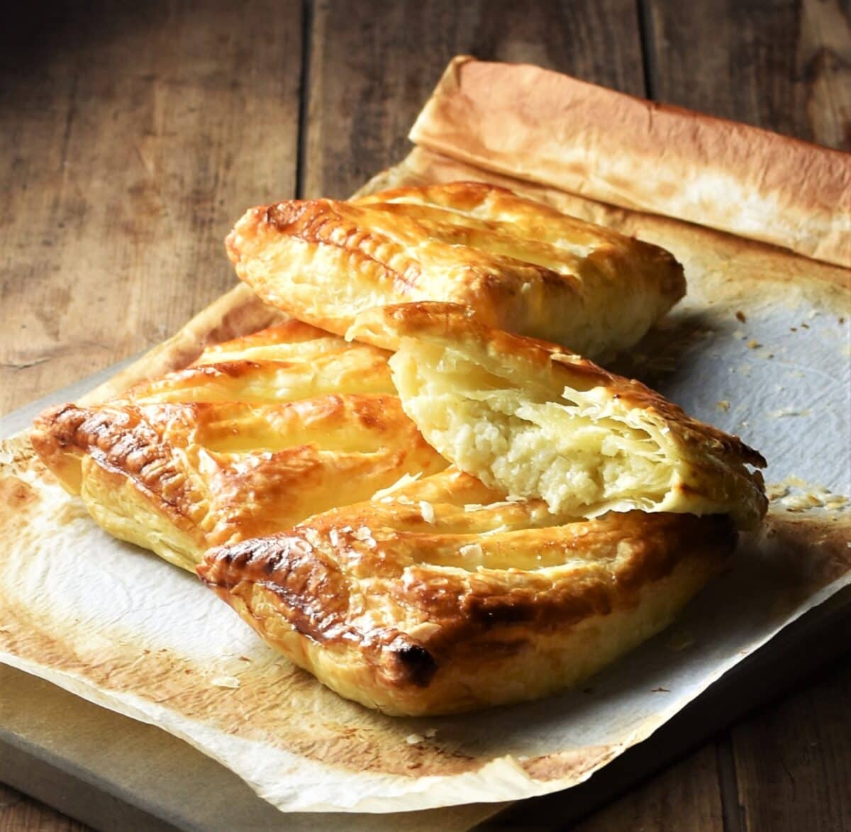 Side view of cheese and onion pasties with cauliflower on top of parchment paper.