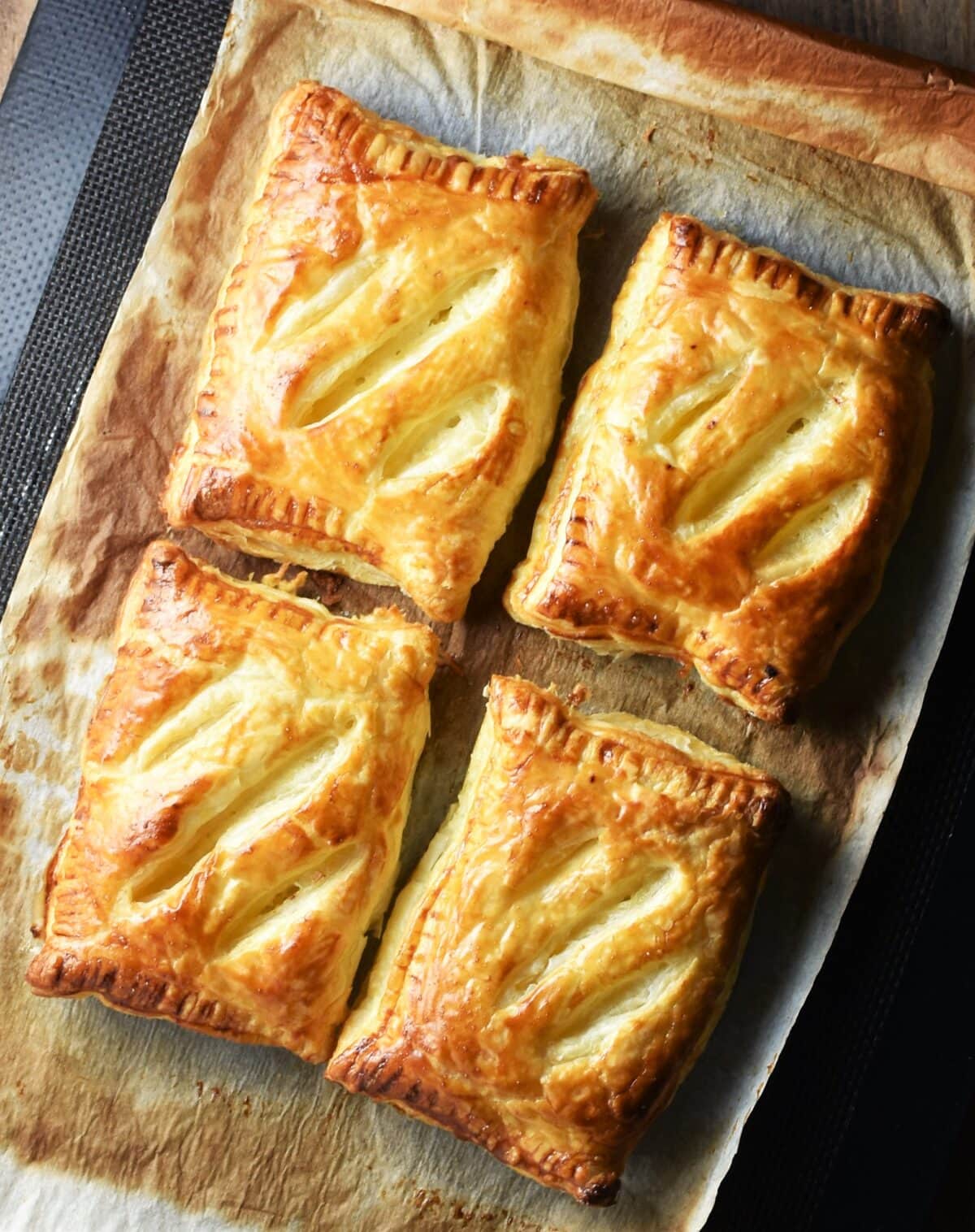 4 golden brown pasties on top of baking paper.