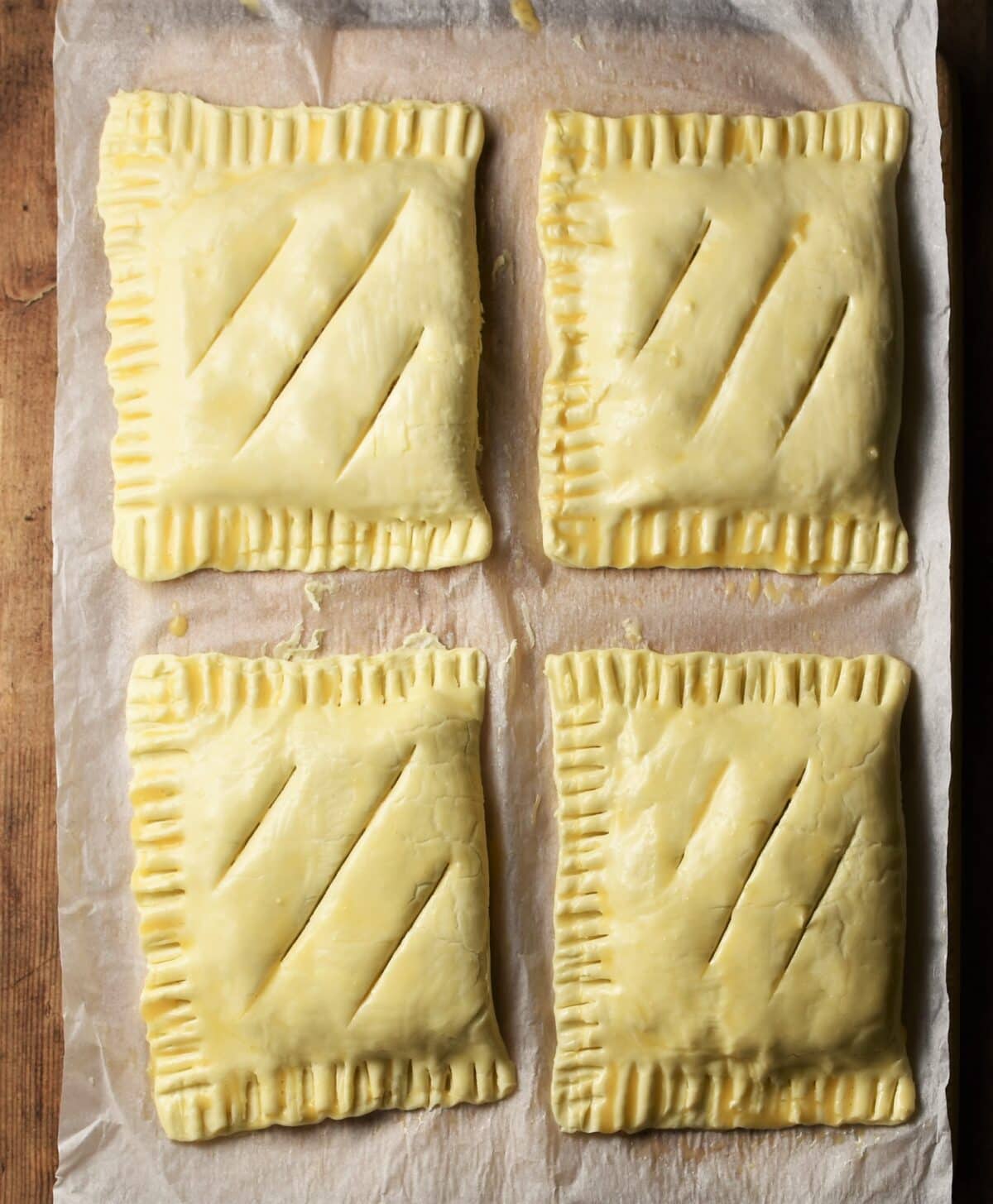 4 raw cheese and onion pasties on top of paper.