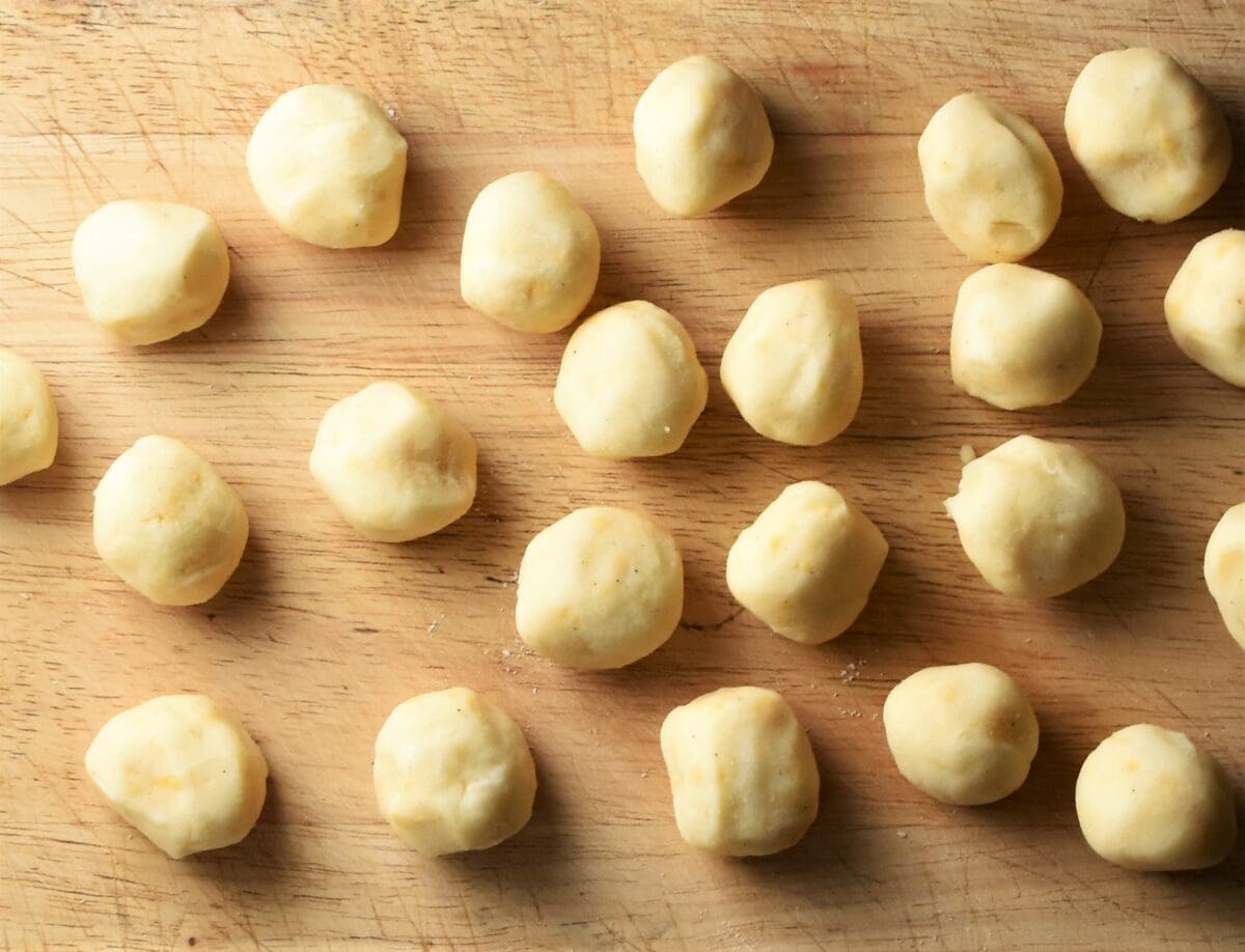 Small perogies filling balls on top of wooden board.
