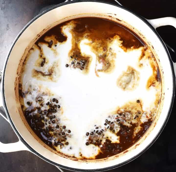 Beluga lentil curry with coconut milk on top in white pot.