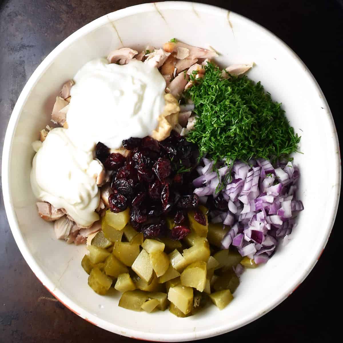 Top down view of ingredients assembled in white bowl for dill pickle chicken salad.