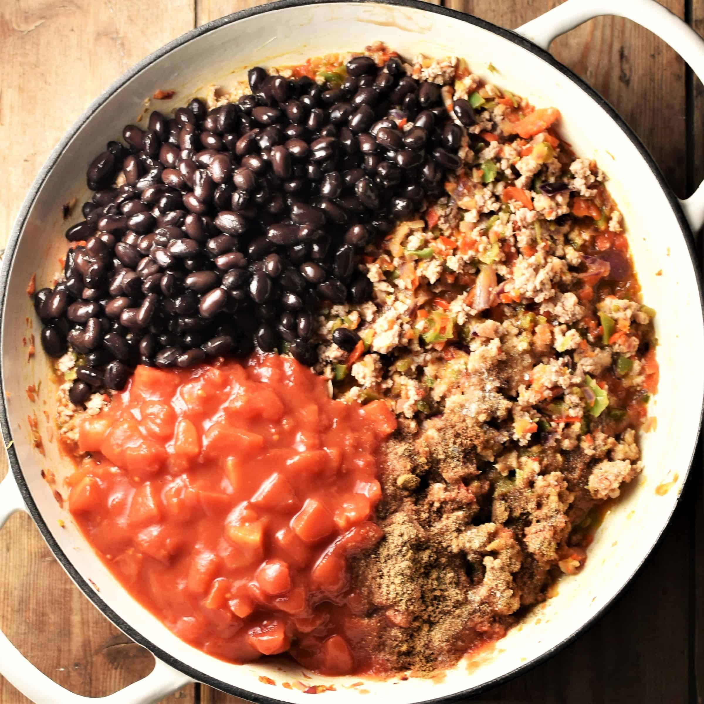 Black beans, chopped tomatoes and meat mixture in large white pan.