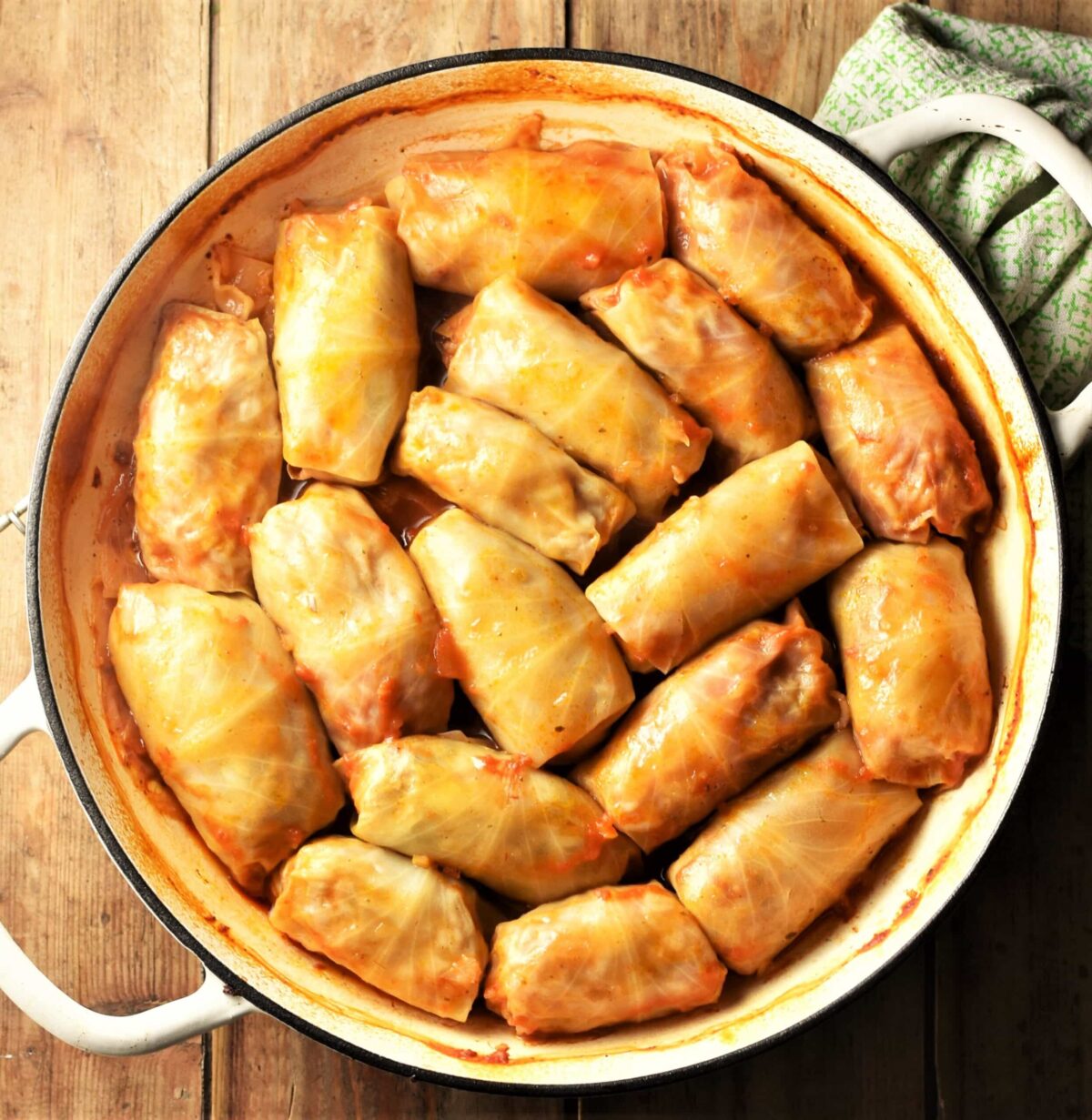 Top down view of cabbage rolls in large white shallow pan.