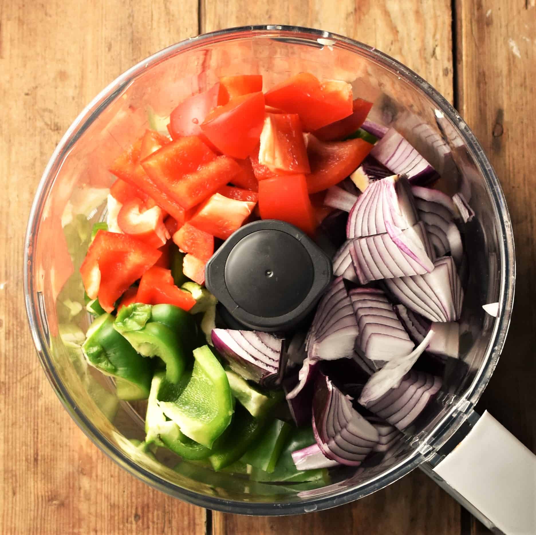 Chopped peppers and red onion in blender bowl.