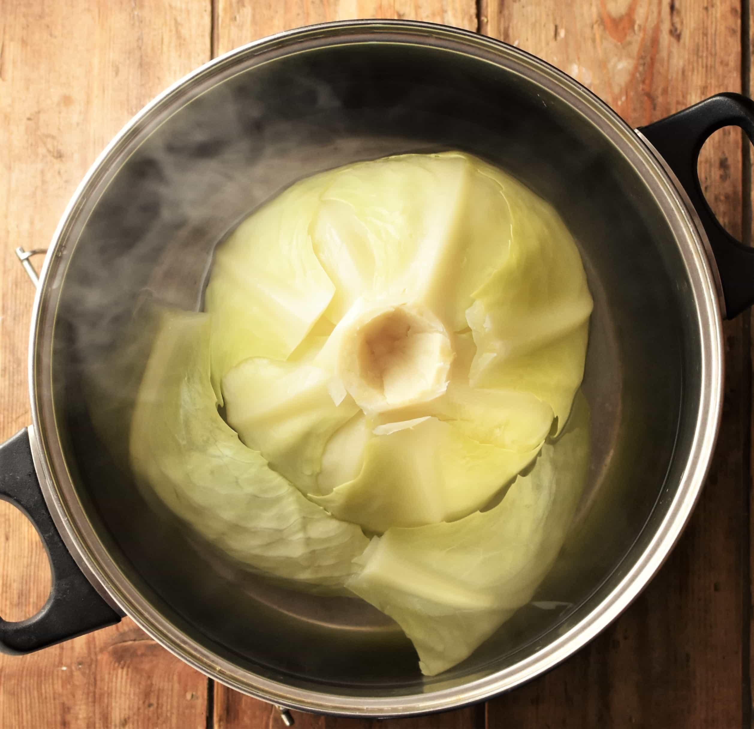 Cabbage in large pot with water, with steam visible.