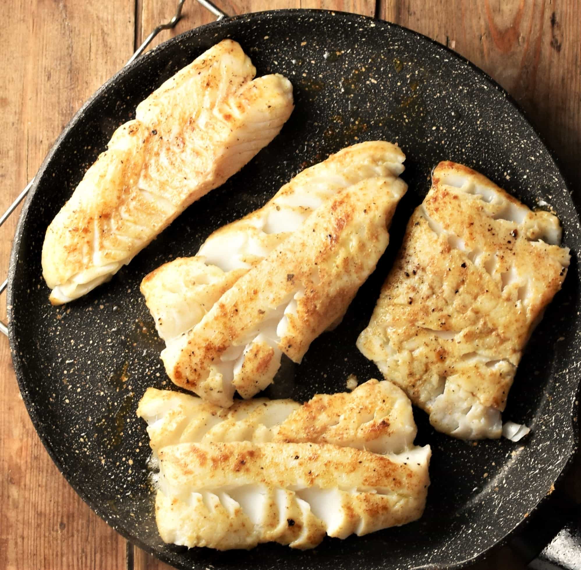 4 large fish fillets in frying pan.