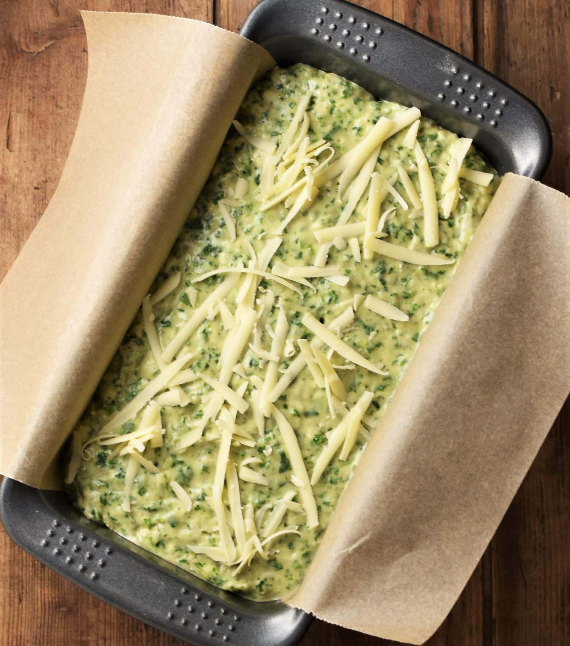 Unbaked bread in loaf pan lined with parchment.