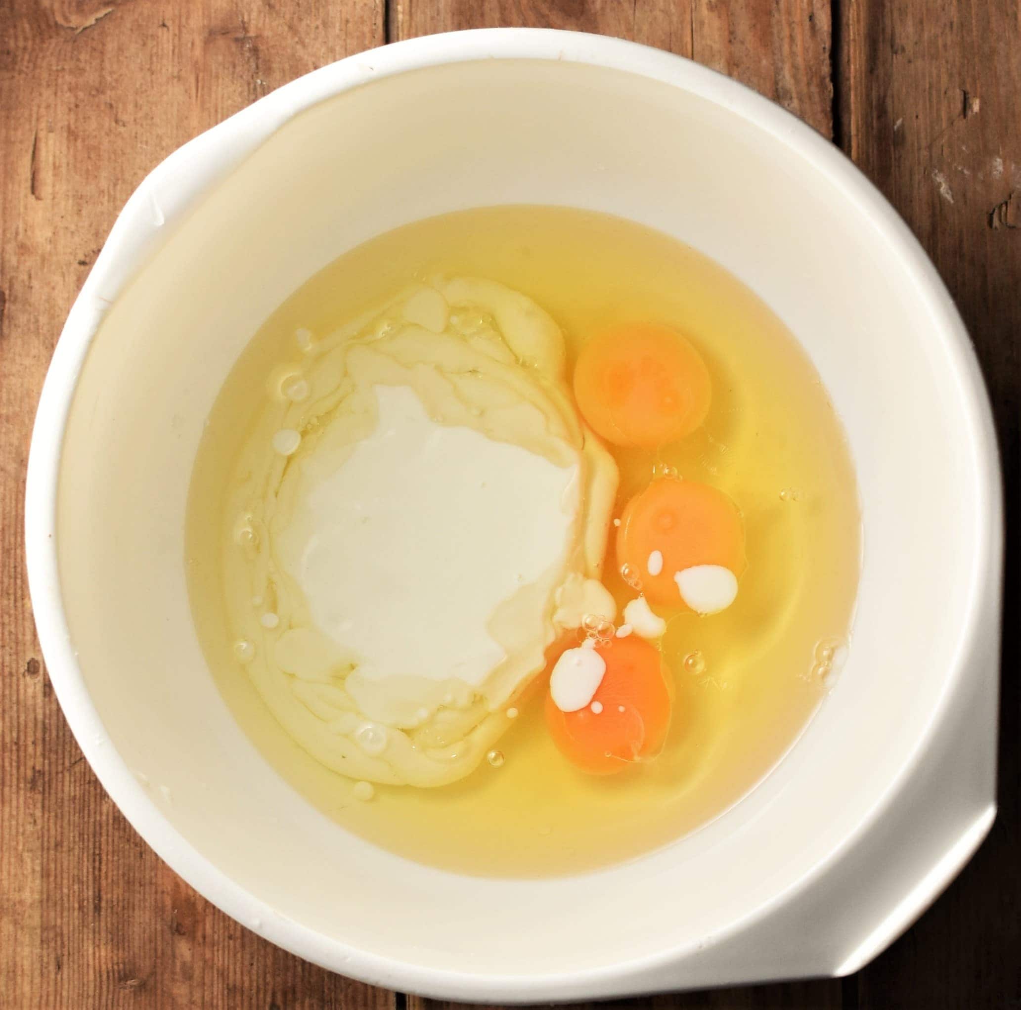 3 eggs and buttermilk in large white bowl.