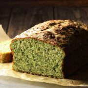 Side view of spinach bread with slice behind on top of parchment.
