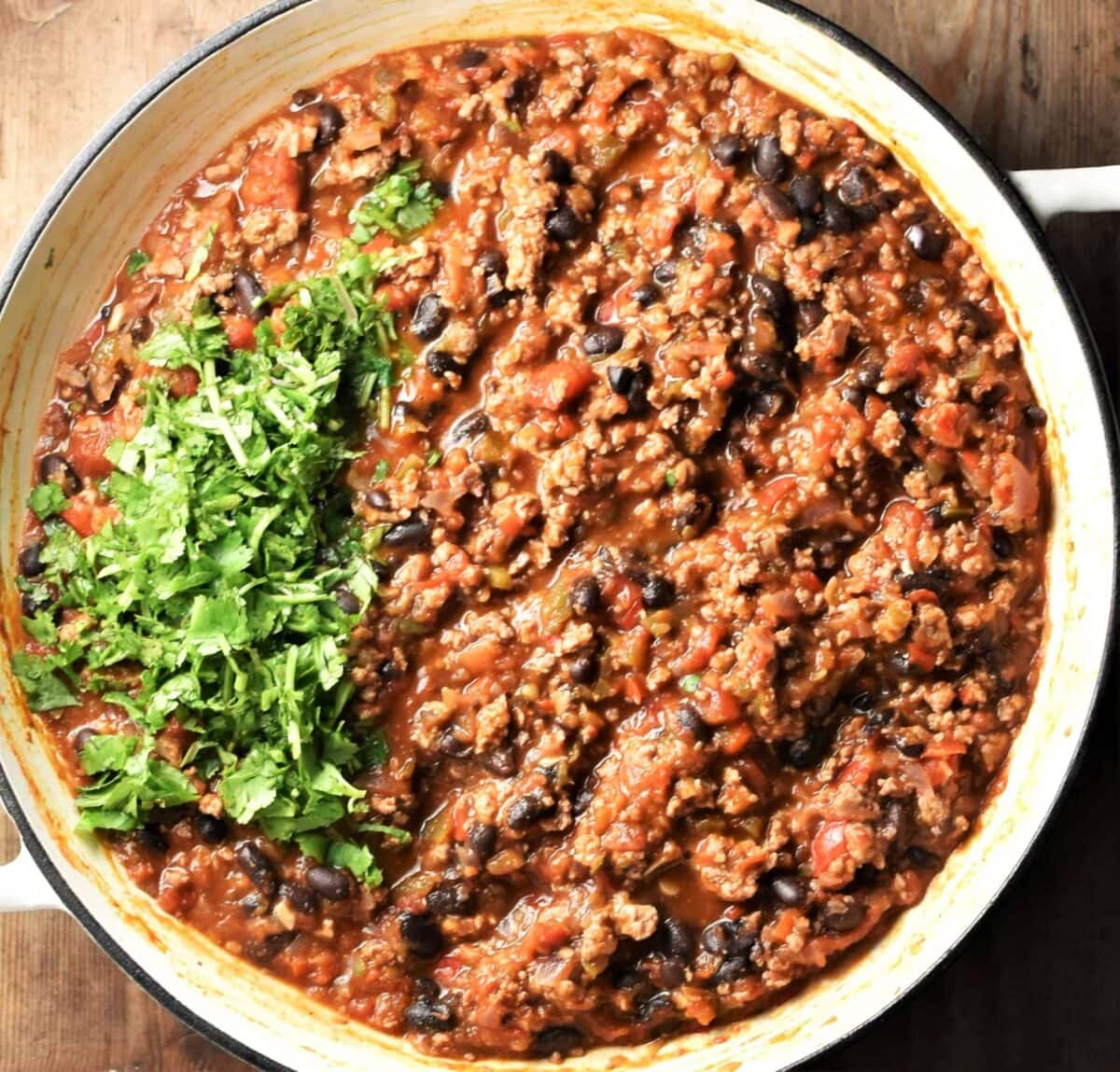 Tortilla bake filling mixture with fresh herbs in large white pan.