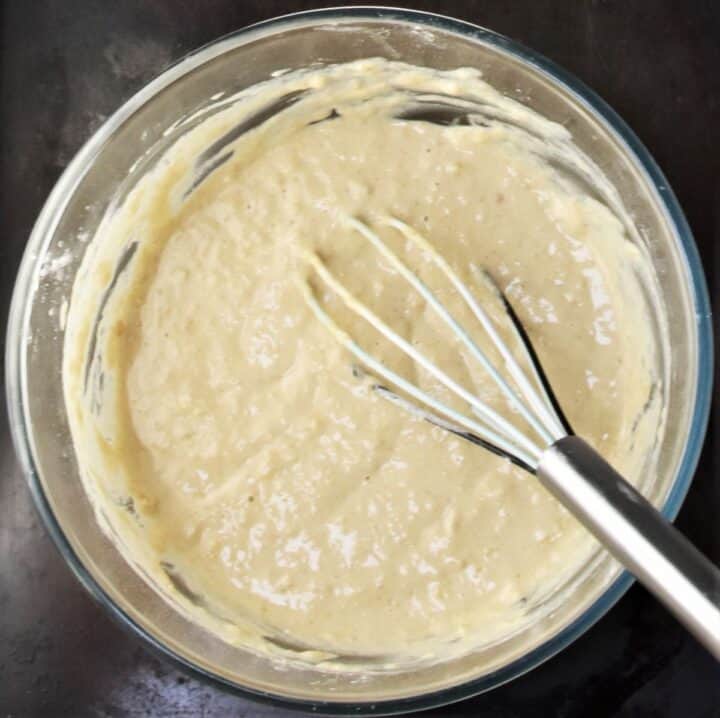 Creamy batter for pancakes with whisk in bowl.