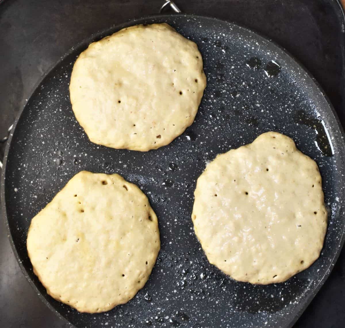 3 raw pancakes in pan.